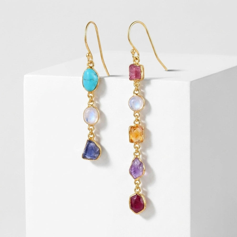 Raw birthstone drop earrings on a white pedestal
